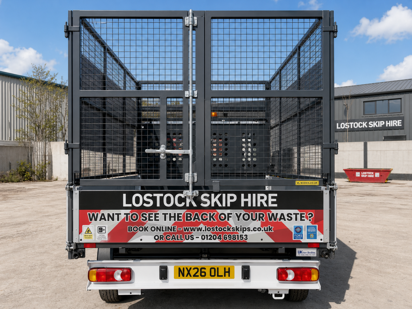 Rear of a dark metal skip hire truck with 'LOSTOCK SKIP HIRE' signage on a red-and-white banner.