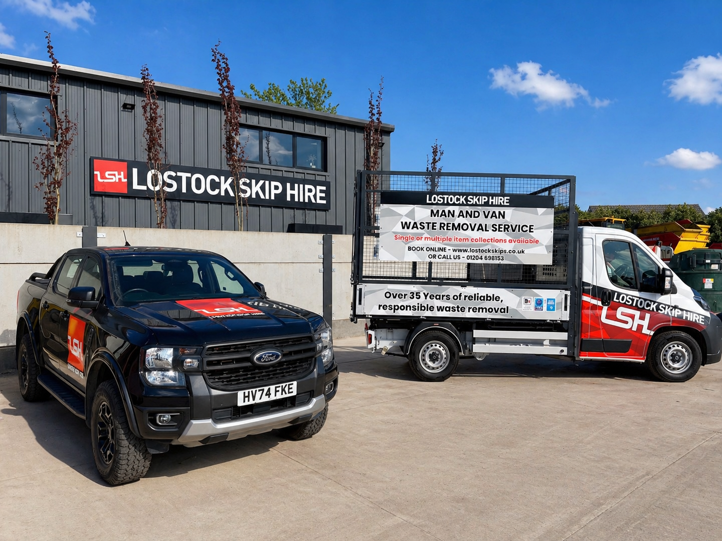 Black Ford pickup with LSH logo parked outside the Lostock Skip Hire warehouse under a blue sky.